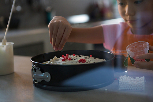 Girl decorating cake in kitchen at home