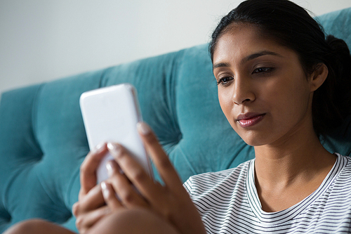 Young woman using phone in bedroom at home