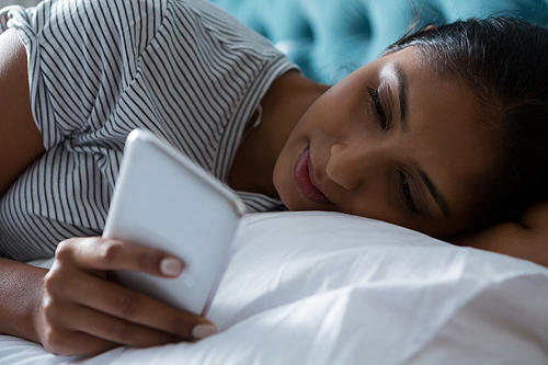 Relaxed young woman using phone on bed at home