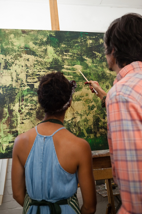 Man assisting woman in painting during drawing class