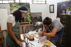 Man assisting woman in pottery during class