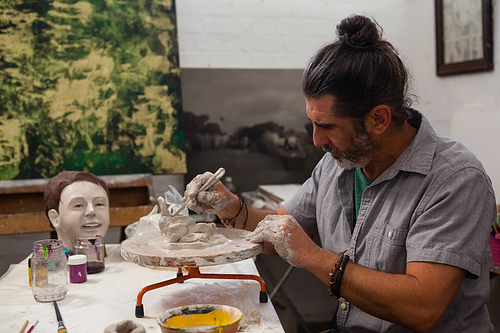 Attentive man molding clay in class