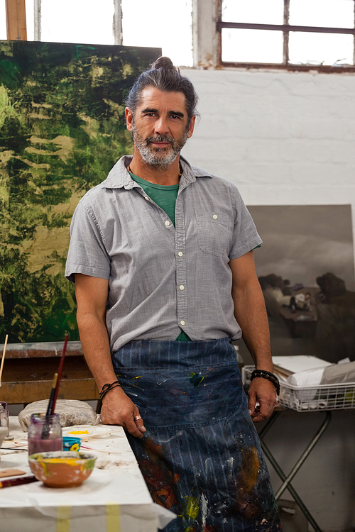 Portrait of confident man standing at table in class