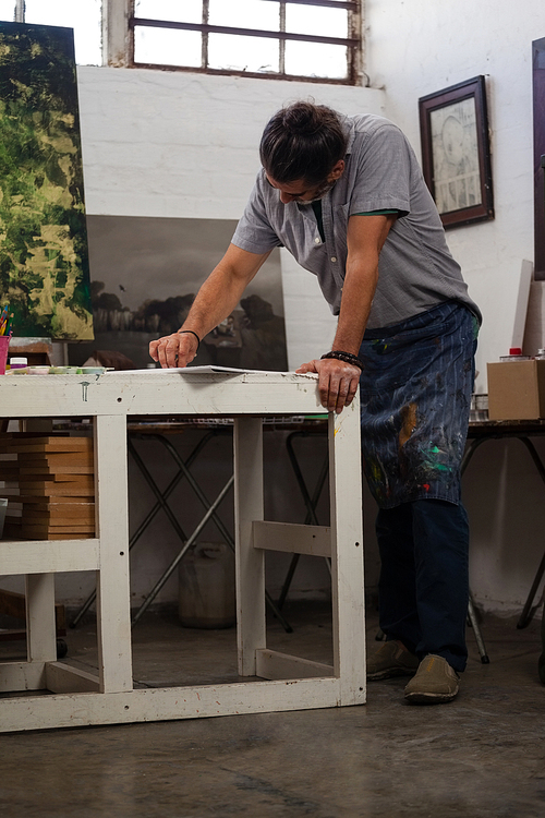 Attentive man painting at table in class