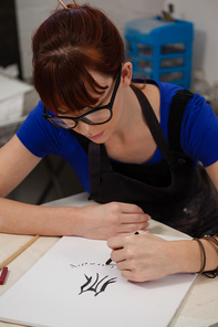 Attentive woman sketching in drawing book at table