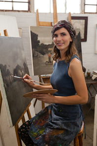 Portrait of woman painting on canvas in drawing class