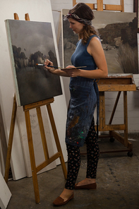 Attentive woman painting on canvas in drawing class