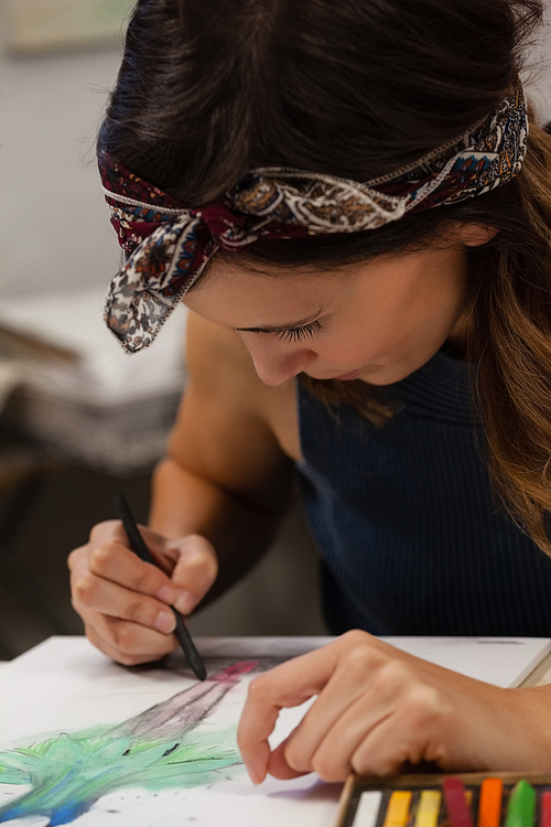 Attentive woman drawing on book in drawing class