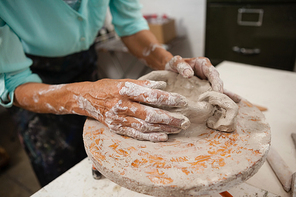 Mid section of man molding clay in class