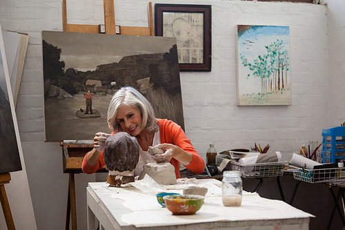 Attentive senior woman making a clay sculpture in drawing class