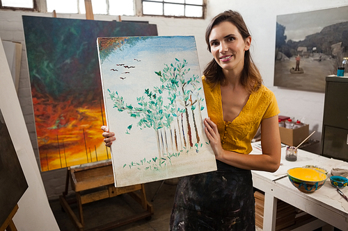 Portrait of woman holding a painting in drawing class