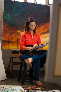 Woman painting in drawing book at drawing class