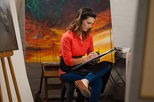 Woman painting in drawing book at drawing class