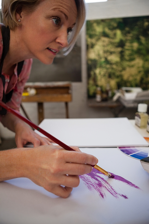 Woman painting in drawing book at drawing class