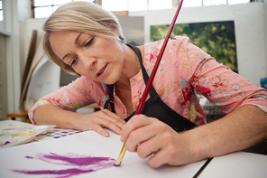 Woman painting in drawing book at drawing class