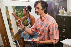 Man and woman painting on canvas in drawing class