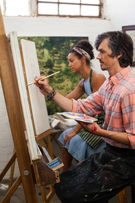 Man and woman painting on canvas in drawing class