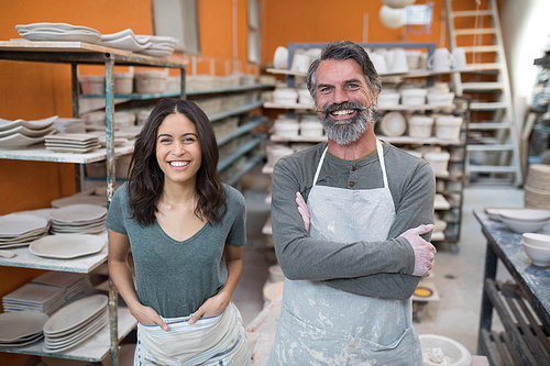 Portrait of male and female potter standing in pottery workshop
