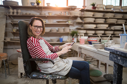 Portrait of female potter using digital tablet in pottery workshop