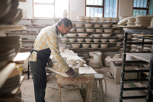 Male potter working at worktop in pottery workshop