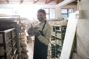 Male potter holding craft product in pottery workshop