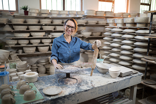 Portrait of female potter standing at worktop in pottery workshop