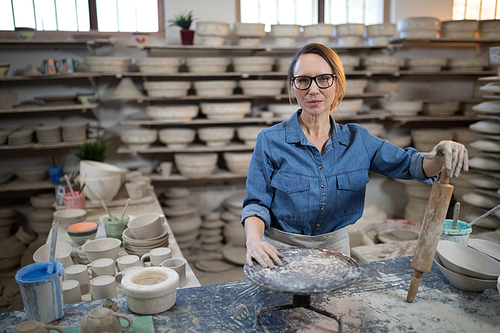 Female potter standing at worktop in pottery workshop