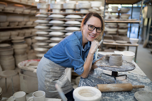 Portrait of female potter molding a clay in pottery workshop