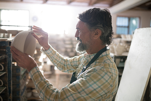 Male potter checking bowl in pottery workshop