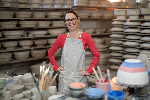 Portrait of female potter standing near worktop in pottery workshop