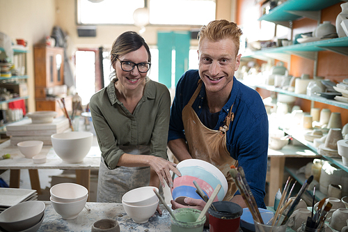 Male and female potter holding bowl in pottery workshop