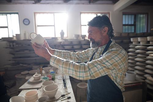 Male potter checking mug in pottery workshop