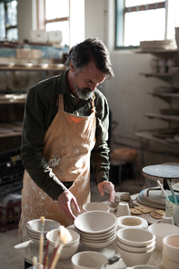 Male potter working at worktop in pottery workshop