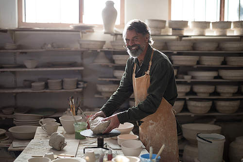 Portrait of male potter molding a clay in pottery workshop