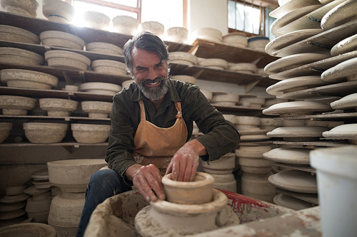 Portrait of male potter molding a clay in pottery workshop