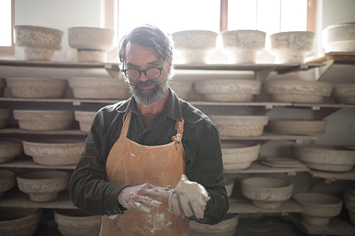 Portrait of male potter molding a clay in pottery workshop