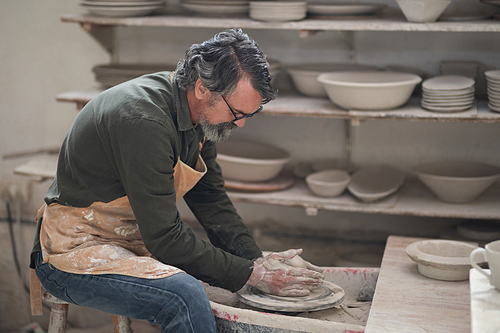 Male potter molding a clay in pottery workshop