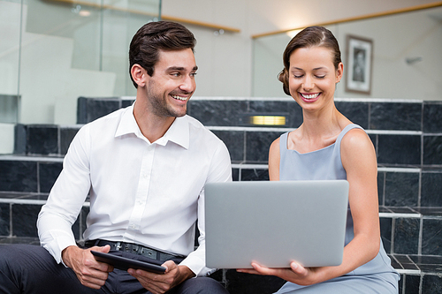 Business executives discussing over laptop at conference centre