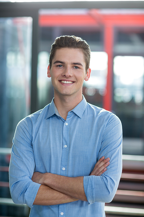 Portrait of smiling business executive standing with arms crossed in office