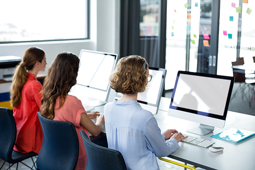 Rear view of business executives working on computer in office