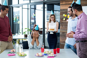Businesspeople giving surprise birthday party to colleague in office