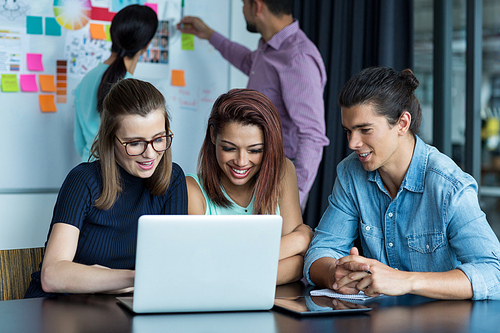 Smiling businesspeople having discussion over laptop in office