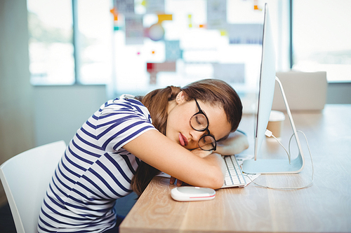 Female graphic designer sleeping on desk at office