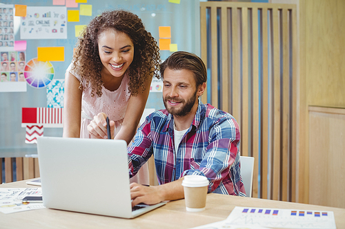 Graphic designers discussing over laptop in office