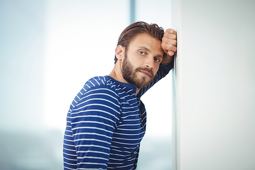 Portrait of sad business executive leaning on wall in office