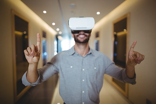 Male executive using virtual reality headset in corridor at office