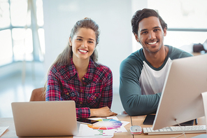 Male and female graphic designers sitting at desk in office