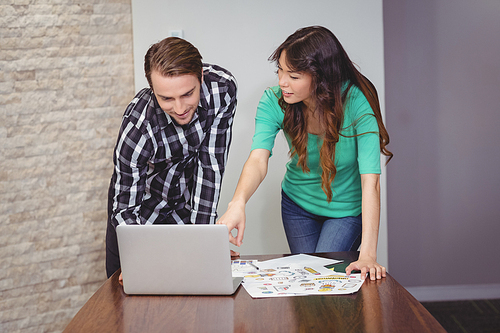 Male and graphic designers discussing over laptop in office