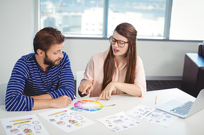 Graphic designers interacting with each other while working in office