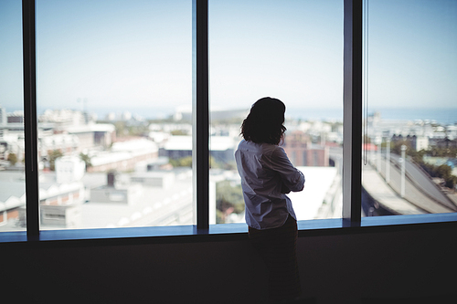 Female executive looking through window in office